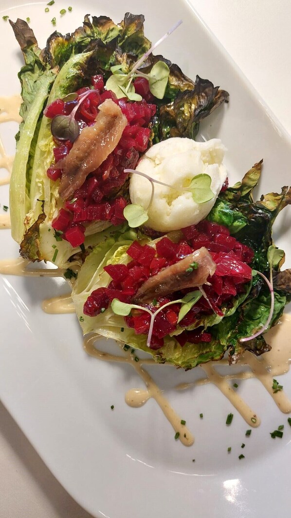 Un plato con ensalada de hojas verdes, remolachas y un huevo pochado, rociado con un aderezo ligero.