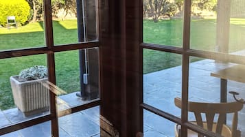A room with large windows, a stone floor, and a view of a garden.