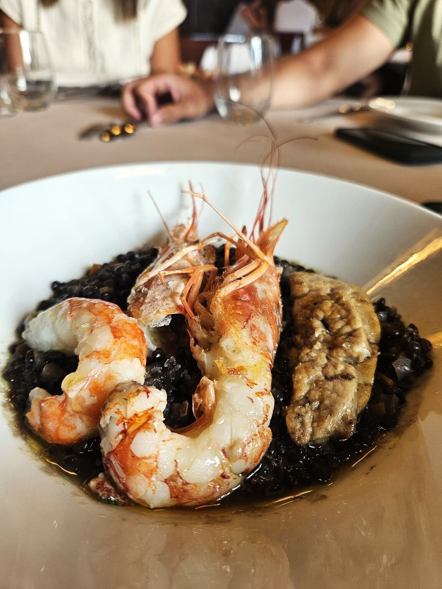 Un plato de mariscos con camarones y calamares, servido sobre una cama de frijoles negros.