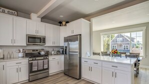 A modern kitchen with white cabinetry, stainless steel appliances, and a large island. - NEAR OREGON COAST and FORT STEVENS!!!
HOT TUB-RIVER VIEW-CARGO SHIPS-REC ROOM (Warrenton)