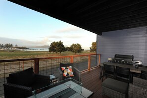A deck with outdoor furniture, a grill, and a view of the landscape.