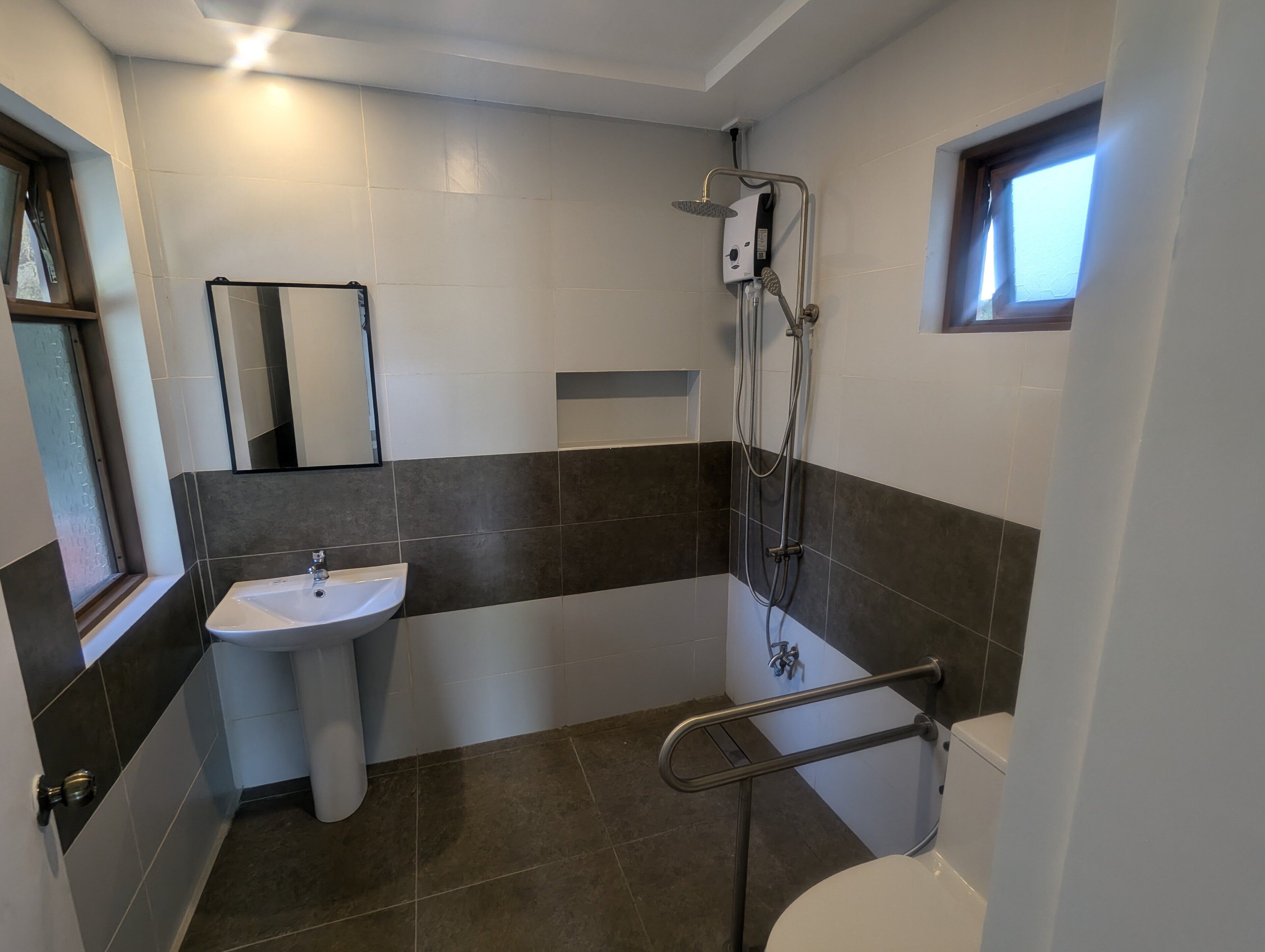 Un baño con lavamanos, inodoro, ducha y ventana.