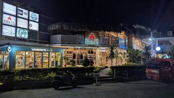 A building with multiple storefronts, including Papa C's, New Era, and others. There is a thatched-roof structure on the upper level.