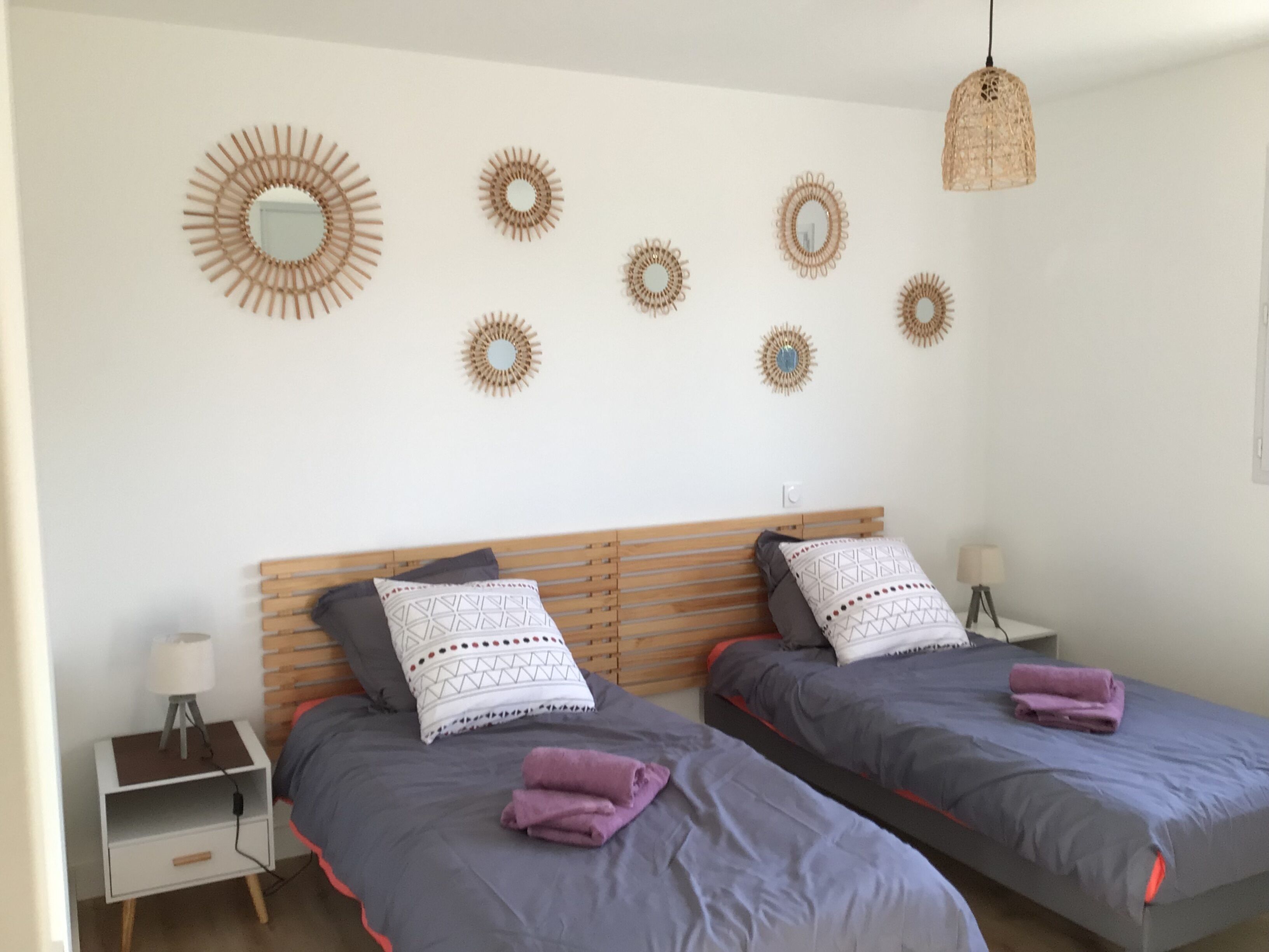 Een slaapkamer met twee bedden, een nachtkastje, een lamp en decoratieve spiegelwand.