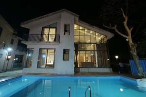 Ein modernes, zweistöckiges Haus mit Schwimmbecken vor der Fassade.