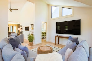 Una sala de estar moderna con un televisor de pantalla plana grande, sofás grises y una mesa de centro de madera.