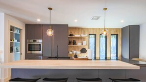 Una cocina moderna con una isla grande, taburetes de bar e iluminación colgante.