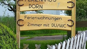 Ein Holzschild mit der Aufschrift 'FERIENHAUS DORN' und 'Ferienwohnungen Zimmer mit DU/WC'.