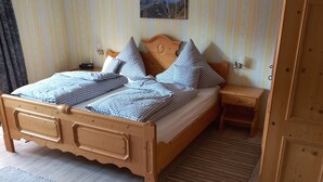 Ein Schlafzimmer mit einem hölzernen Bett, einem Nachttisch, einem Kleiderschrank und einer gestreiften Wand.