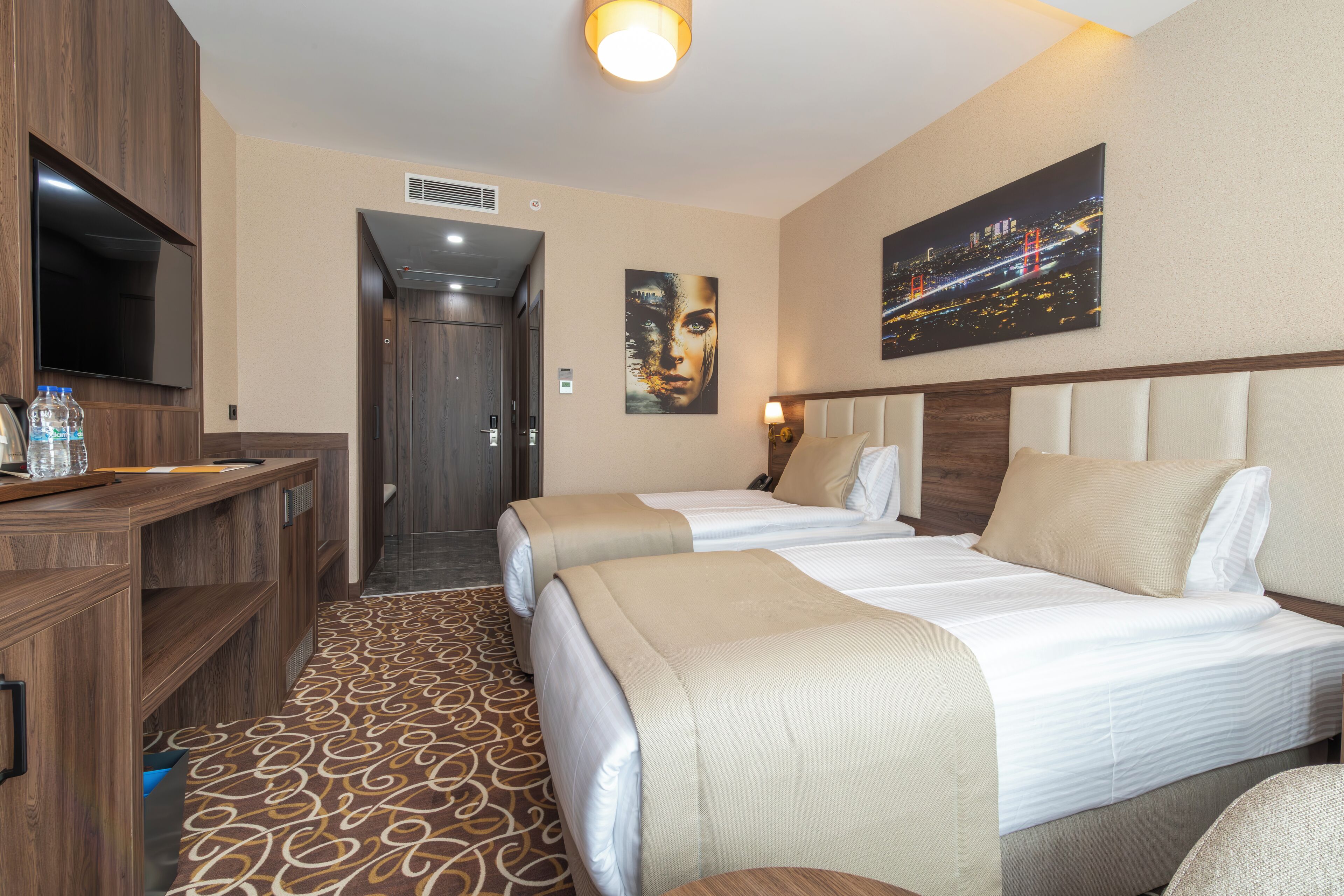 Habitación de hotel con dos camas, televisión, escritorio y baño.