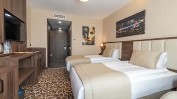 Habitación de hotel con dos camas, televisión, escritorio y baño.