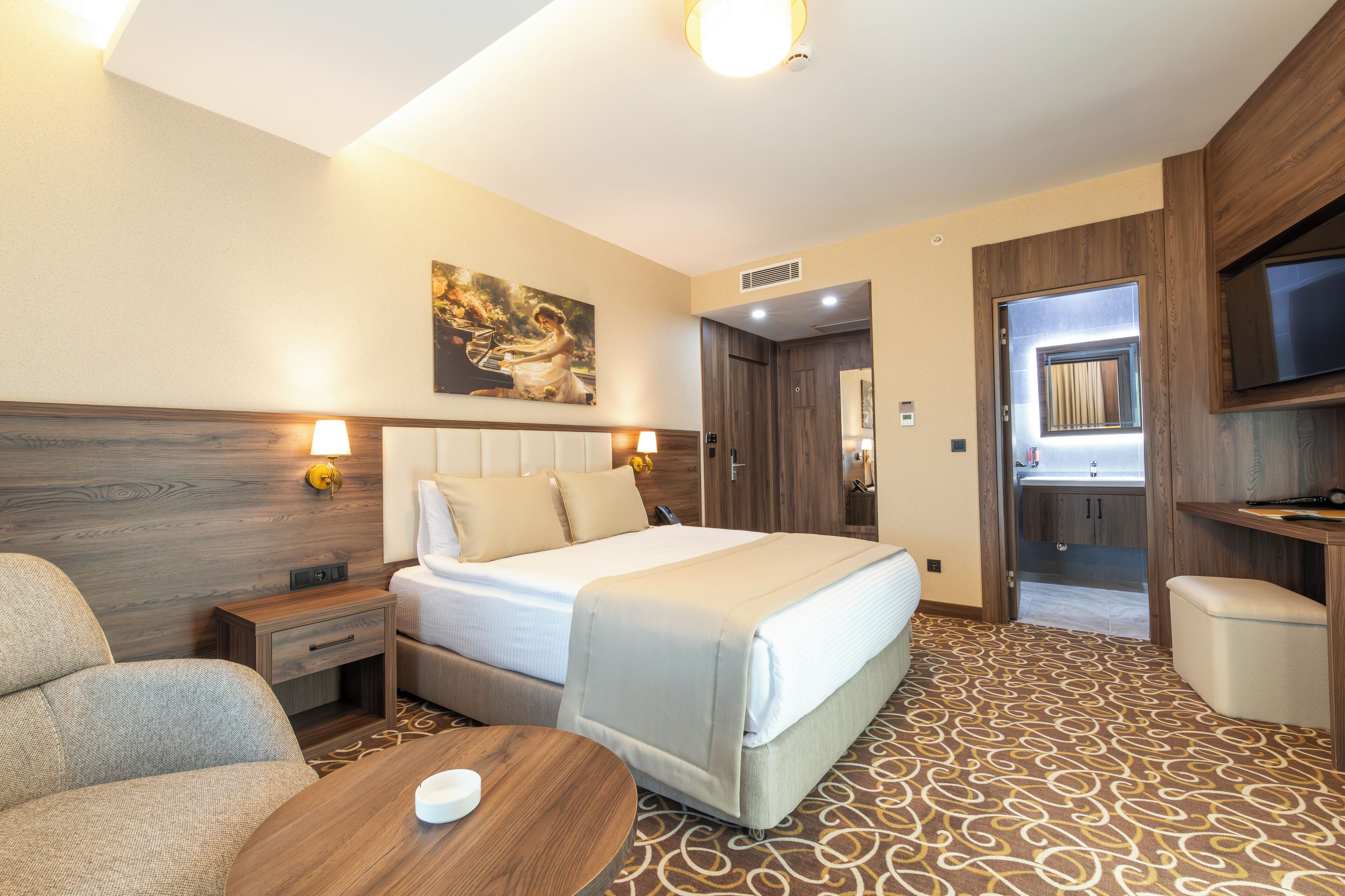 A hotel room with a bed, a sofa, a TV, and a small table.