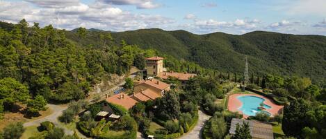 A resort with a swimming pool, surrounded by lush greenery and hills.