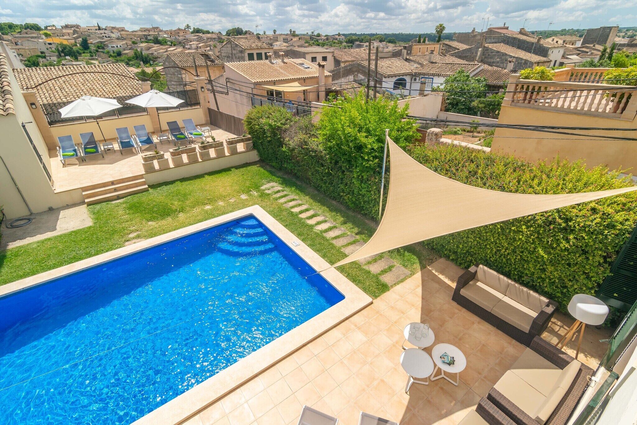 A rooftop pool area with a swimming pool, lounge chairs, and a sunshade.