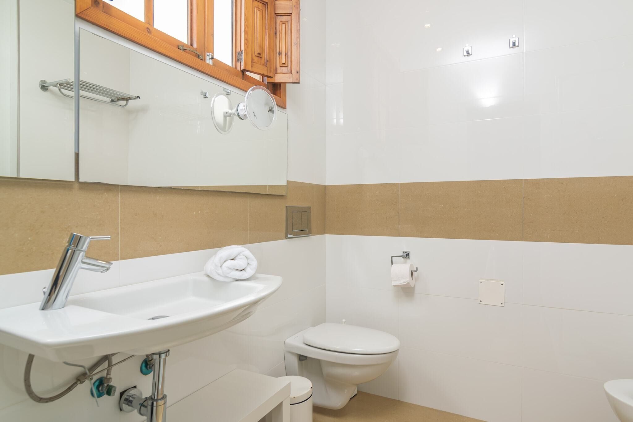 A bathroom with a white sink, a toilet, and a mirror above the sink.
