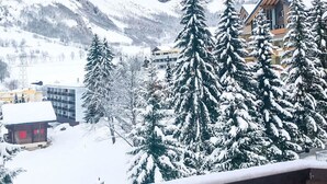 Schneegebirglandschaft mit einer Holzhütte und einem modernen Gebäude im Vordergrund.