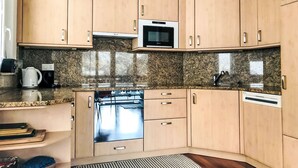 Eine moderne Küche mit Holzausstattung, Backofen, Mikrowelle und einer Arbeitsplatte aus Granit.