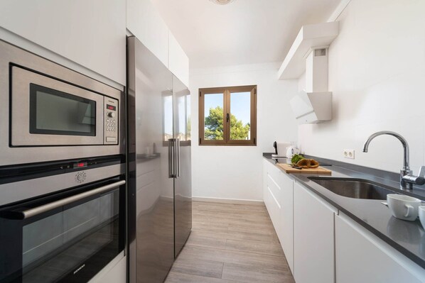 A modern kitchen with stainless steel appliances, a window, and a sink.