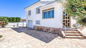 A two-story house with a stone patio, a wooden door, and a small garden area.