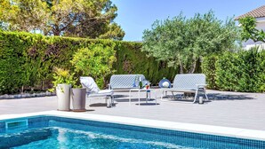 A swimming pool with lounge chairs and potted plants.