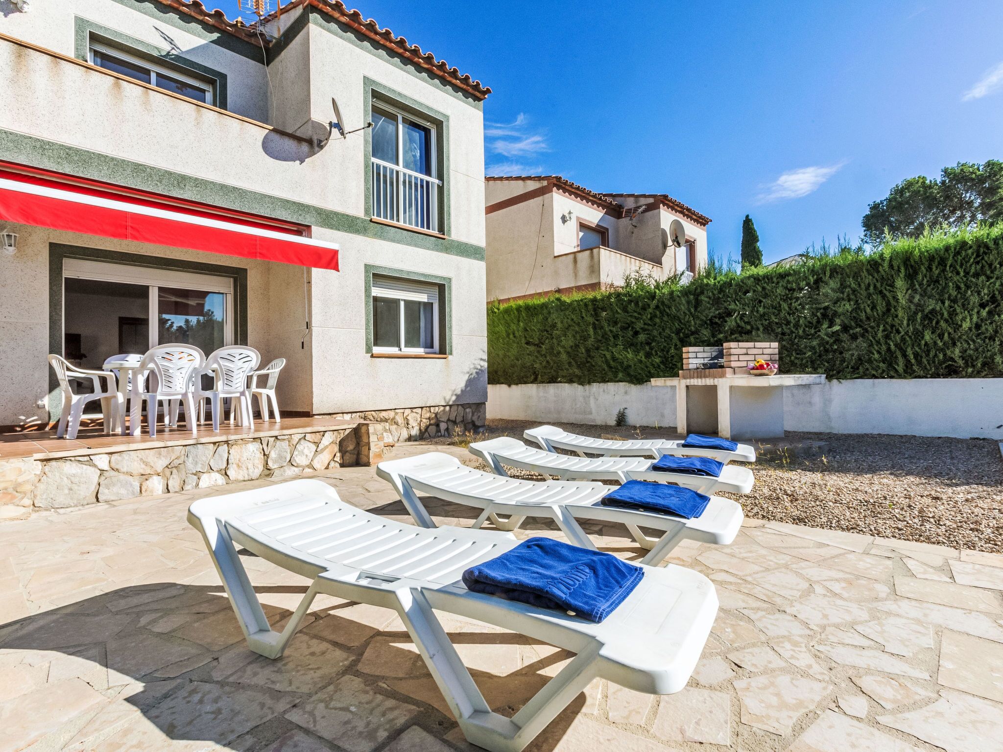 Una villa con patio amueblado con sillones de sol y una mesa con sillas.