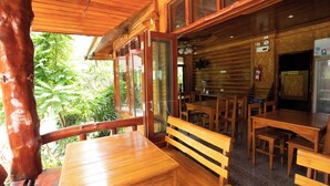 A wooden cabin with a dining area, wooden benches, and a table. - Chatsuree Boutique Resort (Ubon Ratchathani)