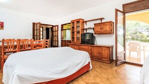 A hotel room with a bed, wooden furniture, a television, and a sliding glass door to a patio.