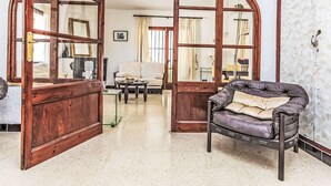 A room with a wooden-framed arched doorway leading to another room, a leather armchair, a sofa, and a glass coffee table. - Vacation home Arcada by Interhome (Miami Platja)