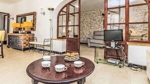 A cozy living room with a round wooden table, a sofa, a television, and a fireplace. - Vacation home Arcada by Interhome (Miami Platja)