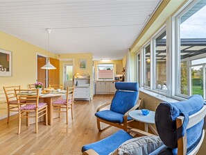 Relax in this airy living room with a dining area for four, a sofa, and a comfortable armchair.