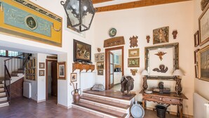 Un intérieur spacieux agrémenté d’un escalier, de poutres en bois et de divers tableaux encadrés qui ornent les murs.
