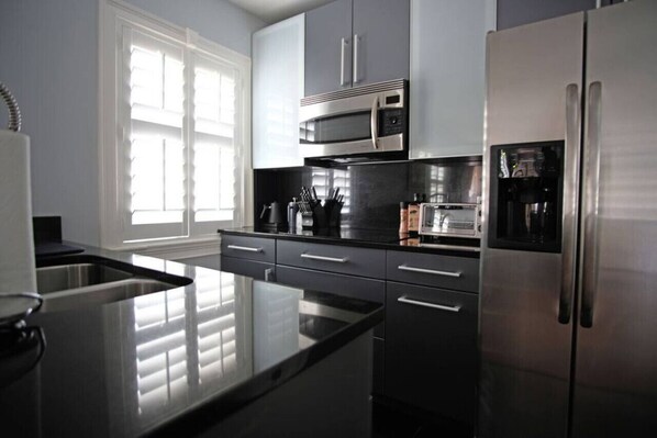 Una cocina moderna con electrodomésticos de acero inoxidable, encimera negra y armarios grises.