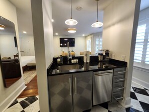 A modern kitchen with stainless steel appliances, a black countertop, and pendant lighting. - Carriage House B at the Hamilton House (Savannah)