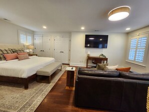 A bedroom with a large bed, a sofa, a TV, and a desk. - Carriage House B at the Hamilton House (Savannah)
