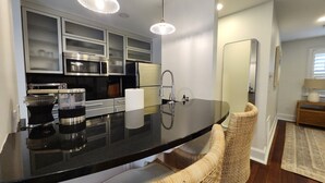 A modern kitchen with a black countertop, stainless steel appliances, and wicker chairs. - Carriage House B at the Hamilton House (Savannah)