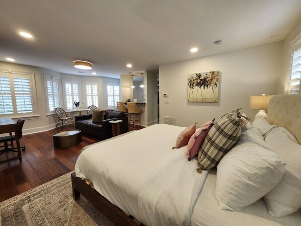 A bedroom with a large bed, a desk, and a sofa.