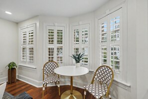 A room with a round table, two chairs, and three windows with shutters. - Carriage House B at the Hamilton House (Savannah)