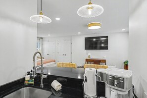A modern bathroom with a sink, mirror, and towel dispenser. - Carriage House B at the Hamilton House (Savannah)