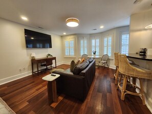 A living room with a sofa, a TV, a dining area with chairs, and a bar. - Carriage House B at the Hamilton House (Savannah)