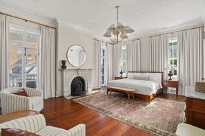 A spacious bedroom with a large bed, a fireplace, and a view of the city. - Hamilton House - 5 Bed Historic Downtown House w/ Courtyard & Parking (Savannah)
