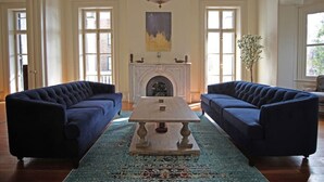 Una habitación con dos sofás azul oscuro, una mesa de centro de madera, una chimenea y un candelabro.
