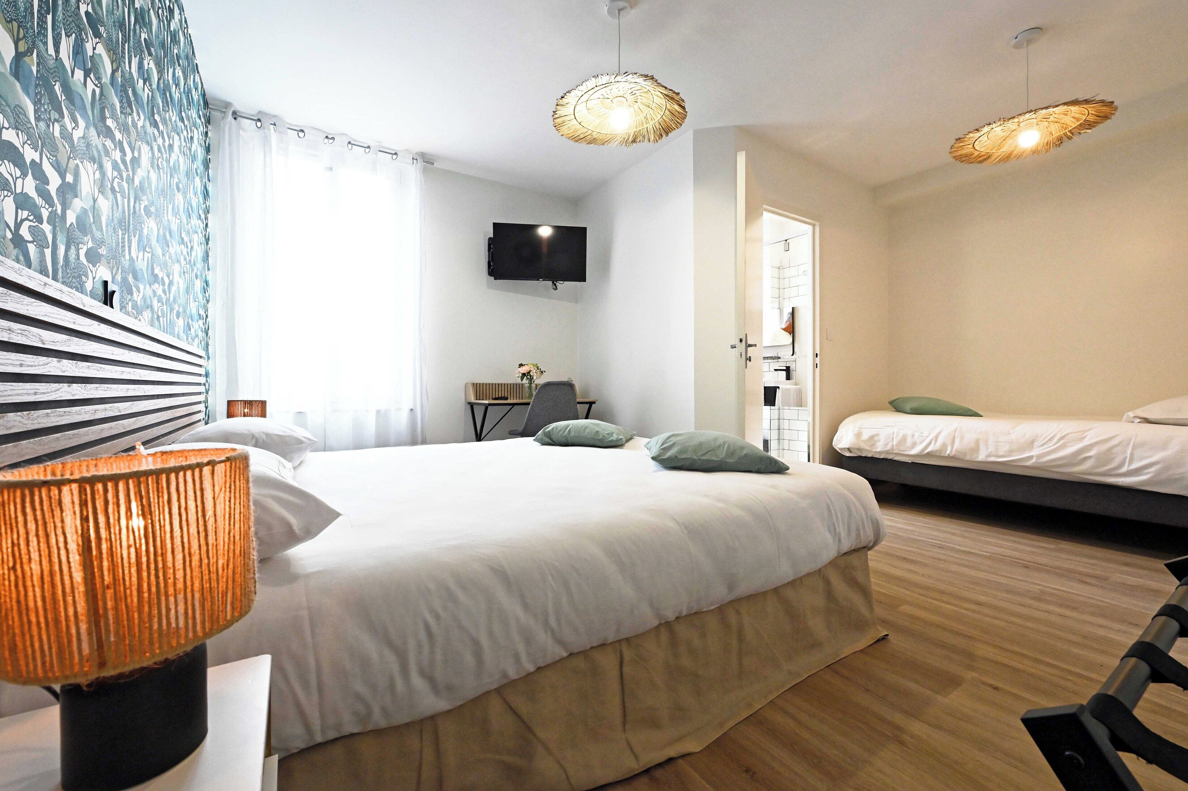 A modern hotel room with a large bed, a desk, a TV, and a separate sleeping area.