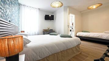 A modern hotel room with a large bed, a desk, a TV, and a separate sleeping area.