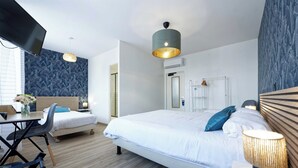 A modern hotel room with a large bed, a desk with a chair, a TV, and a decorative lamp. - Hôtel le Terminus et son restaurant Côte à Côte (Autun)