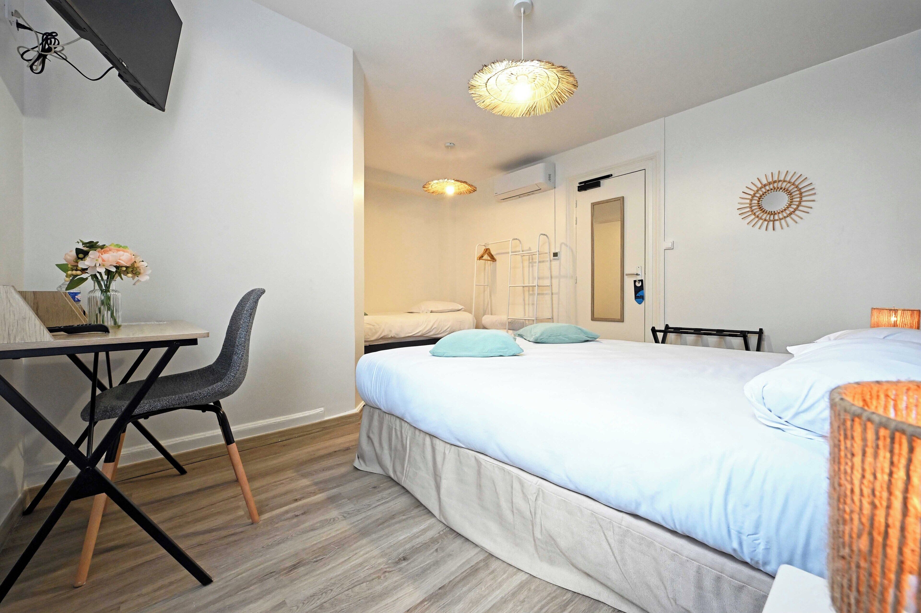 Una habitación de hotel con cama, escritorio, silla y una pequeña mesa con un jarrón de flores.