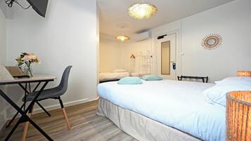 Una habitación de hotel con cama, escritorio, silla y una pequeña mesa con un jarrón de flores.