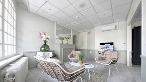 A spacious living area with a fireplace, comfortable seating, and a large window providing natural light. - Hôtel le Terminus et son restaurant Côte à Côte (Autun)