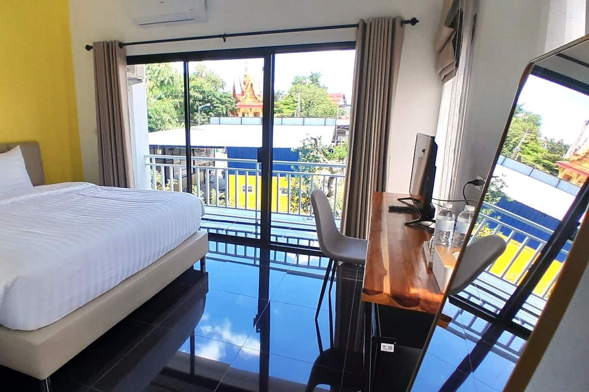 Ein Hotelzimmer mit Bett, Schreibtisch mit Stuhl und Blick auf einen Tempel durch große Fenster.