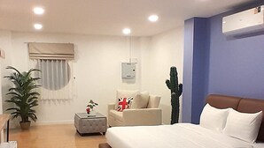 A modern hotel room with a large bed, a sofa, a small table, and a potted plant. - J-Boutique Hotel (Khon Kaen)