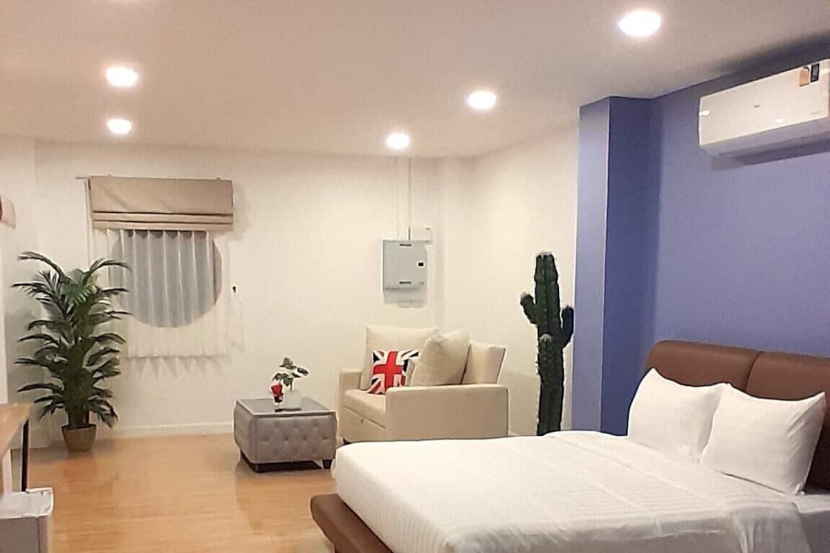 Ein modernes Hotelzimmer mit einem großen Bett, einer Couch, einem kleinen Tisch und einer Topfpflanze.